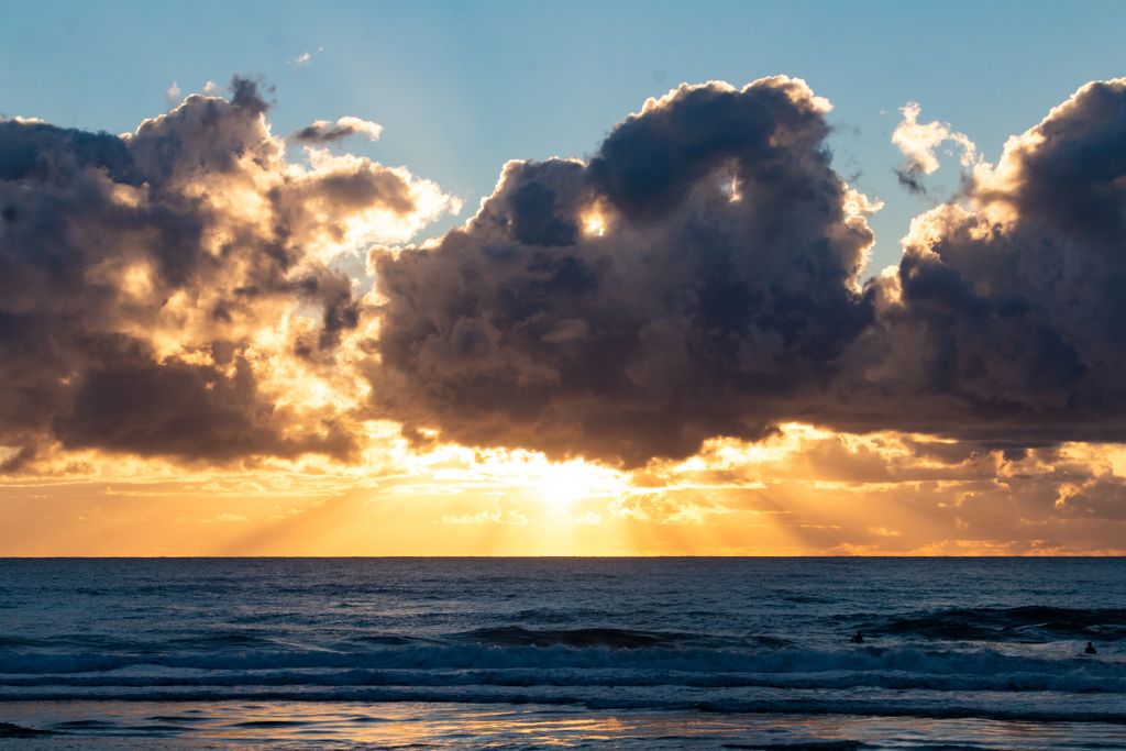 Stunning ocean sunset with dramatic clouds and streaming sunrays over the horizon.